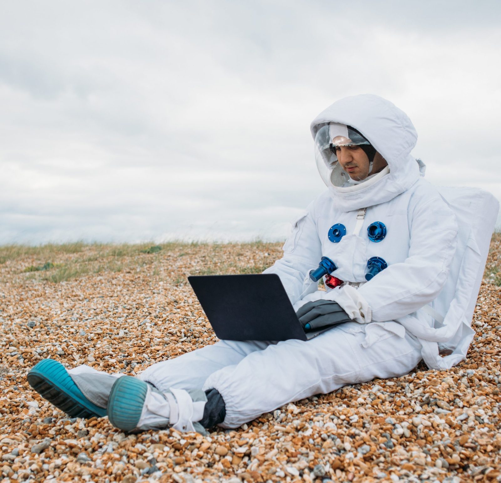 Astronaut sitting in desert ground with a laptop