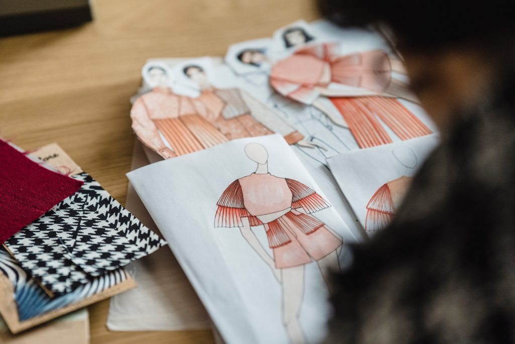 Paper dolls or skeches of clothes  on a table.